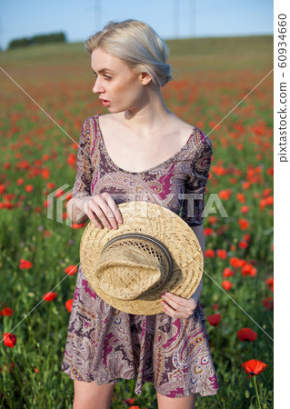 Portrait of a beautiful blonde woman in a hat in a field of red poppies Portrait of a beautiful blonde woman in a hat in a field of red poppies 60934660
