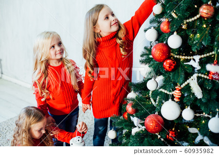three girls decorate the Christmas tree Christmas presents new year Christmas tree Garland lights three girls decorate the Christmas tree Christmas presents new year Christmas tree Garland lights 60935982