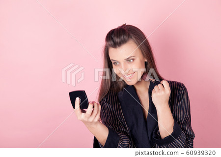 girl in coat makes brush makeup looks in the mirror girl in coat makes brush makeup looks in the mirror 60939320