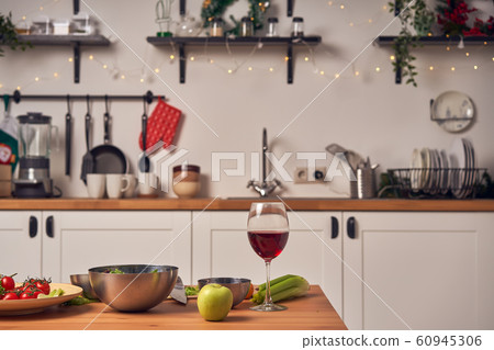 Festive table with glass of wine, iron cups on background of wall with garlands at New Year. 60945306