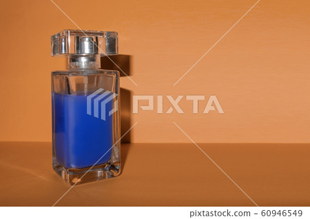 Transparent glass bottle with blue liquid on brown 60946549