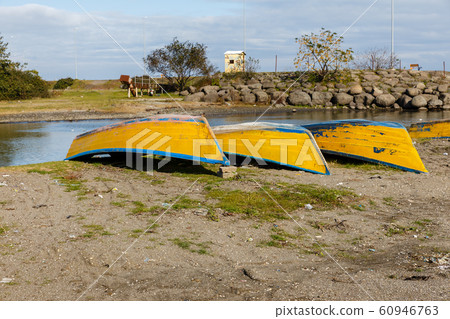 yellow fishing boats lie on the sand by the river yellow fishing boats lie on the sand by the river 60946763