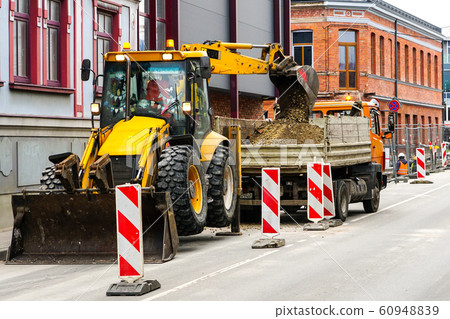 an excavator digs a trench on street and pours an excavator digs a trench on street and pours 60948839