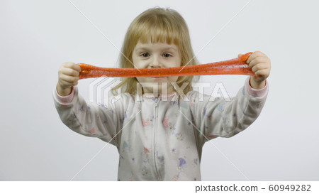Kid playing with hand made toy slime. Child having fun making orange slime 60949282