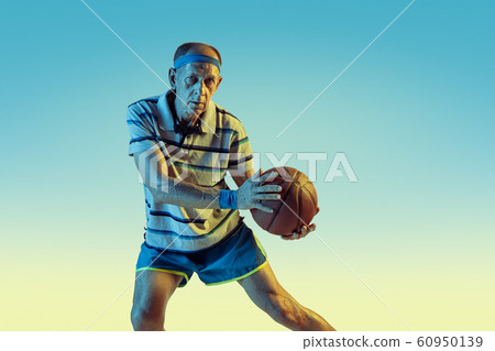 Senior man playing basketball in sportwear on gradient background and neon light Senior man playing basketball in sportwear on gradient background and neon light 60950139