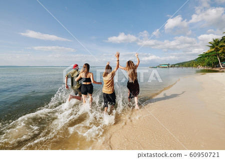 Young people running and splashing on the beach 60950721
