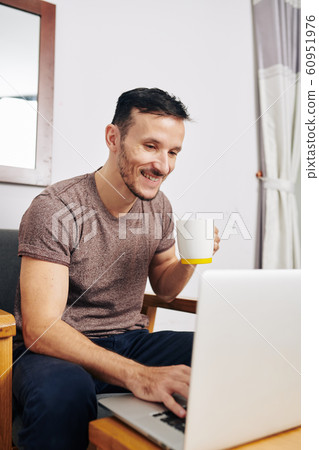 Cheerful man using social media on laptop Cheerful man using social media on laptop 60951976