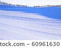 The morning sun rises over the Biei hills of Hokkaido in winter, and the ridges of the hills are streaked 60961630