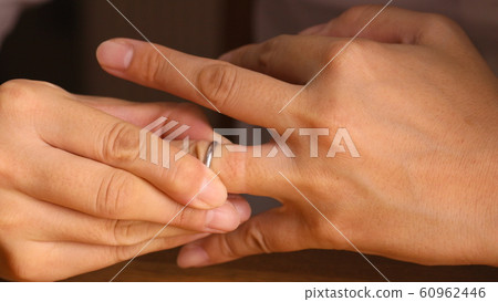 Woman removing a ring Woman removing a ring 60962446