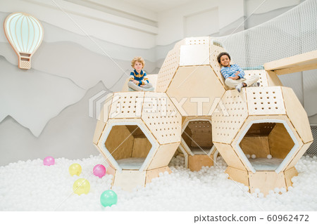 Two intercultural restful cute kids in casualwear spending time on playground Two intercultural restful cute kids in casualwear spending time on playground 60962472