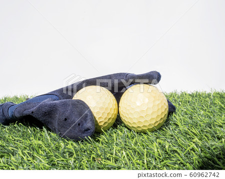 Photo of yellow golf balls and blue glove on artificial grass with white background Photo of yellow golf balls and blue glove on artificial grass with white background 60962742