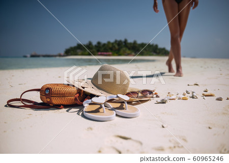 female legs on white beach with travel accessories, exotic vacation, product photo for travel agency 60965246