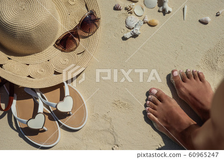 female legs on white beach with travel accessories, exotic vacation, product photo for travel agency 60965247