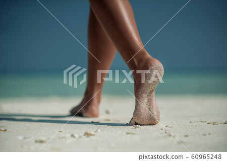 female legs on white beach with travel accessories, exotic vacation, product photo for travel agency 60965248