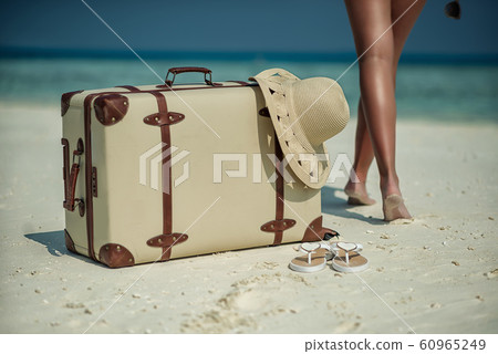 female legs on white beach with travel accessories, exotic vacation, product photo for travel agency 60965249