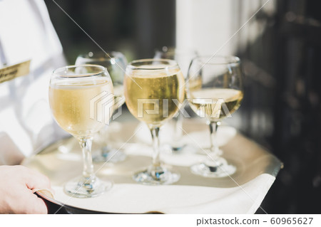 Waiter serving glasses with champagne on a tray Waiter serving glasses with champagne on a tray 60965627