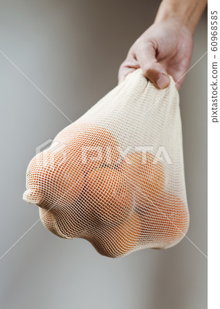 man and reusable mesh bag with oranges. 60968585