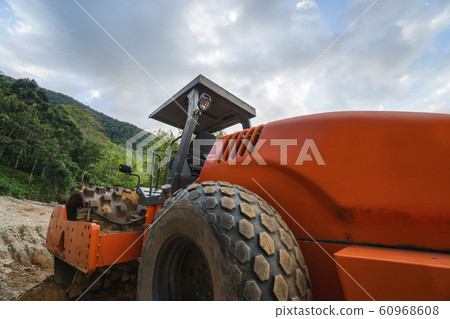 Soil compactor with vibratory padfoot drum. Heavy duty machinery working on highway construction site. Vehicle for soil compaction. Road construction equipment. Paving. Compaction of the road. 60968608