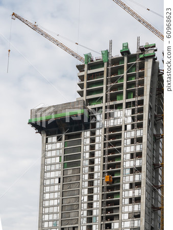 Construction site of building a high-rise building with a cranes against blue sky. Construction site of building a high-rise building with a cranes against blue sky. 60968623