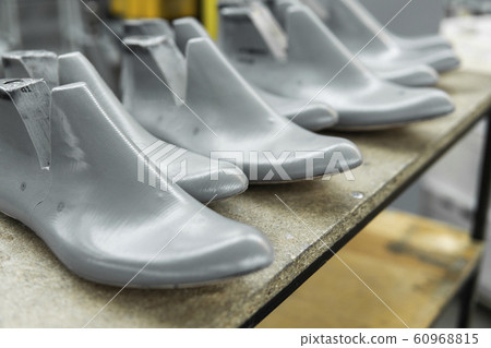 Plastic lasts used in the manufacture of shoes. Row of plastic shoe lasts used to manufacture modern day shoes. A lot of plastic last shoe on a wooden shelf. The equipment used for shoe design. 60968815