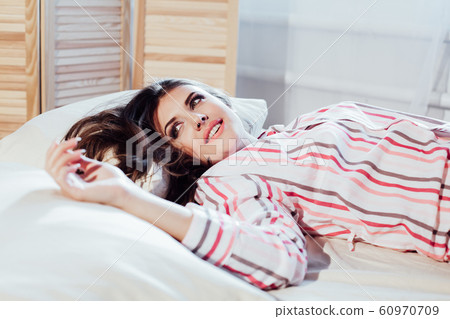 girl in pajamas woke up in the morning is sitting on a bed girl in pajamas woke up in the morning is sitting on a bed 60970709
