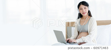 Beautiful Asian pregnant women wear headphones, use a laptop, find information about the health care 60971463