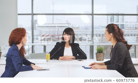 Determined business partners actively studying business documents at wooden conference table Determined business partners actively studying business documents at wooden conference table 60973776
