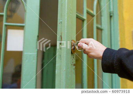 Unlocks the old green wooden entrance door Unlocks the old green wooden entrance door 60973918
