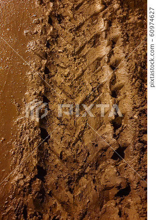 Dirty car tread track on the ground with clay in the evening 60974627