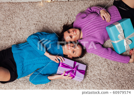 Two beautiful women with gifts at the Christmas tree garlands new year 60979574