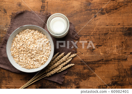 Rolled oats, oat flakes and oat milk on wooden table 60982401