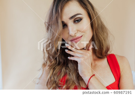 Portrait of a beautiful fashionable woman in a red dress in a white office 60987191