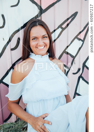 A beautiful woman with long hair in a dress looks out over the sea from a cliff 60987217
