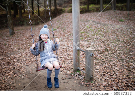 在冬季公園的鞦韆上玩的女孩 在冬季公園的鞦韆上玩的女孩 60987332