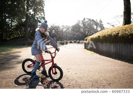 女孩玩自行車在冬季公園 女孩玩自行車在冬季公園 60987333