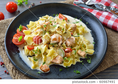 Austrian meal with typical pasta and smoked salmon with creamy sauce, served on a black plate Austrian meal with typical pasta and smoked salmon with creamy sauce, served on a black plate 60987491