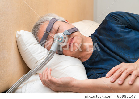 Middle age Asian man wearing CPAP headgear during his sleep Middle age Asian man wearing CPAP headgear during his sleep 60989148