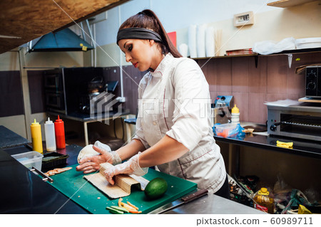 woman chef prepares fresh sushi in the kitchen of the restaurant 60989711
