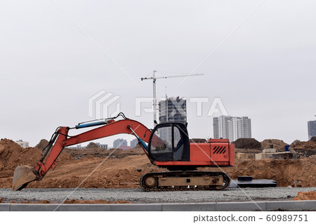 Excavator with a large iron bucket on a construction site during road works. 60989751