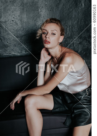 portrait of a beautiful fashionable blonde woman in a gray blouse and black skirt 60990163