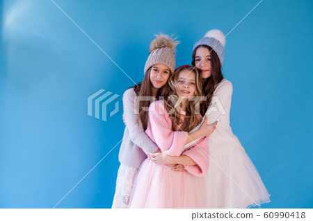 Portrait of three beautiful fashionable girls in dresses and hats in winter Portrait of three beautiful fashionable girls in dresses and hats in winter 60990418