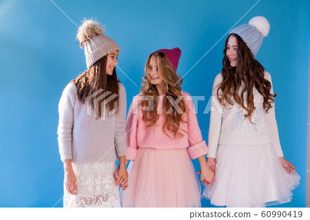 Portrait of three beautiful fashionable girls in dresses and hats in winter Portrait of three beautiful fashionable girls in dresses and hats in winter 60990419