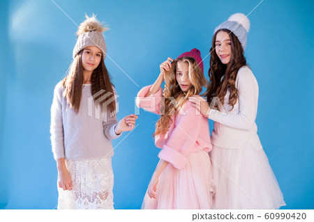 Portrait of three beautiful fashionable girls in dresses and hats in winter Portrait of three beautiful fashionable girls in dresses and hats in winter 60990420