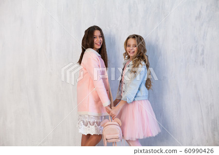 Portrait of two beautiful fashionable girls in pink dress and winter jacket Portrait of two beautiful fashionable girls in pink dress and winter jacket 60990426