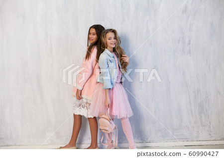 Portrait of two beautiful fashionable girls in pink dress and winter jacket Portrait of two beautiful fashionable girls in pink dress and winter jacket 60990427