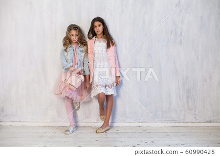 Portrait of two beautiful fashionable girls in pink dress and winter jacket Portrait of two beautiful fashionable girls in pink dress and winter jacket 60990428