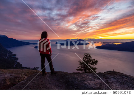 Adventurous Caucasian Girl standing on top of a mountain 60991078
