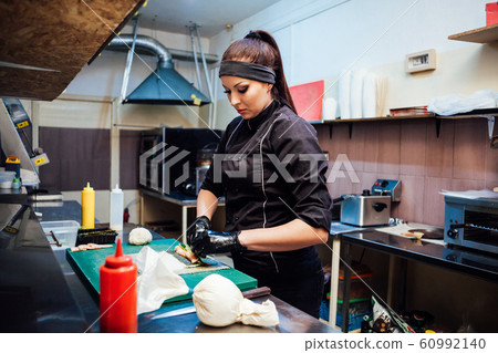 woman chef prepares fresh sushi in the kitchen of the restaurant 60992140