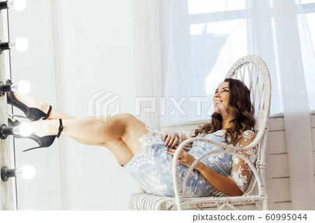 Portrait of a beautiful fashionable woman with hair curls in a blue dress Portrait of a beautiful fashionable woman with hair curls in a blue dress 60995044