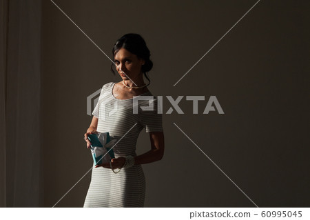 portrait of a beautiful fashionable brunette woman with a gift in her hands portrait of a beautiful fashionable brunette woman with a gift in her hands 60995045